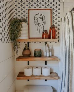 a bathroom with two shelves holding toilet paper and vases on top of the shelves