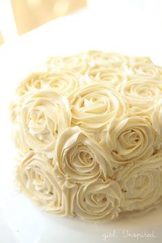 a close up of a cake with white frosting roses