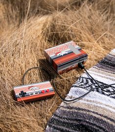 two old fashioned tape recorders laying on top of some dry grass in the sun