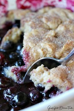 blueberry cobbler in a white dish with a spoon resting on it's side