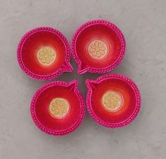 four red bowls with yellow designs on them sitting on a gray surface, top view