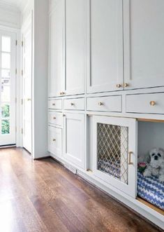 a dog bed in the middle of a room with white cabinets and wood flooring