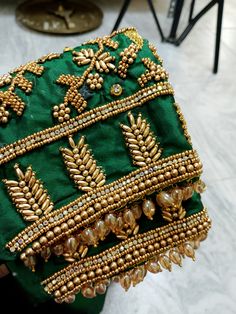 a green cloth with gold beadings and pearls on it sitting next to a chair