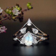 "A pretty 7x5 mm pear cut rainbow moonstone, with accent diamonds forming a trillion, sitting on a split shank with diamond accents - this unique engagement ring is a perfect choice for your enigmatic other half, her mystic side which you just cannot fathom! Stack it with our versatile 3 pear diamond V ring. MOONSTONE ENGAGEMENT RING * Center Stone : Pear Cut Natural Rainbow Moonstone * Stone Wt : 0.66 Ct * Diamond Wt. : 0.06 cts * Color-Clarity Grade: H-I, Vs-Si * Gold - 14k, 2 gm gold (approx) Teardrop Moonstone Wedding Ring In Fine Jewelry Style, Fine Jewelry Teardrop Moonstone Wedding Ring, Teardrop Moonstone Wedding Ring Fine Jewelry, Wedding Fine Jewelry Teardrop Moonstone Ring, Teardrop Moonstone Ring For Wedding, Silver Teardrop Moonstone Ring For Wedding, Silver Pear-shaped Moonstone Wedding Ring, Pear-shaped Moonstone Wedding Ring, Pear-shaped Moonstone Ring For Wedding