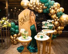 a woman standing in front of a table with cake on it and balloons hanging from the ceiling