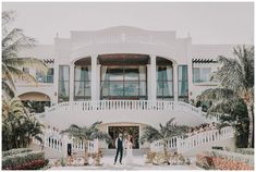 a bride and groom standing in front of a large white building with balconies