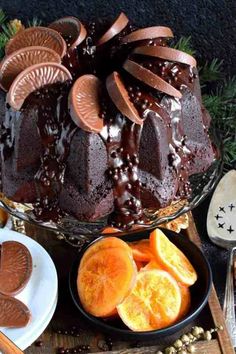 a bundt cake with chocolate icing and sliced oranges on the side next to it