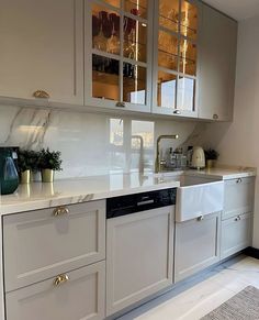 a kitchen with white cabinets and marble counter tops