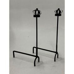 two black metal candlesticks with crowns on them, each holding a candle holder