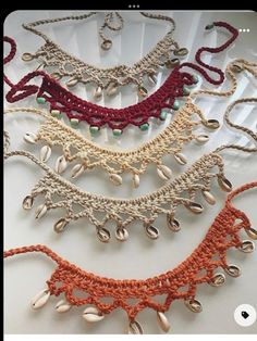 several crocheted necklaces are displayed on a white surface, including one with beads