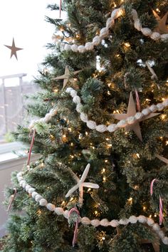 a christmas tree decorated with white and pink ribbon, starfishes and candy canes