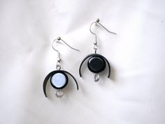 two black and white earrings on a white sheet with silver ear wires hanging from them