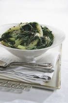 a white bowl filled with broccoli on top of a table next to silverware