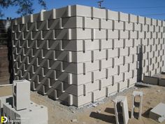 cinder blocks stacked on top of each other in front of a building with construction equipment around them