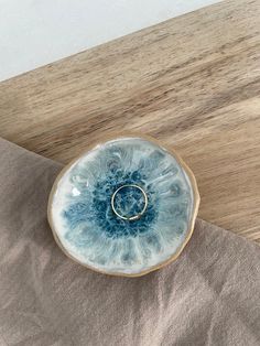 a blue and white ring dish sitting on top of a wooden table next to a napkin