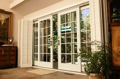 an open window with white shutters and potted plant