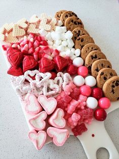 a cutting board topped with lots of cookies and candy