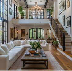 a living room filled with lots of furniture and a chandelier hanging from the ceiling