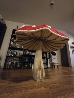 a mushroom like object is sitting on the floor in front of a bookshelf