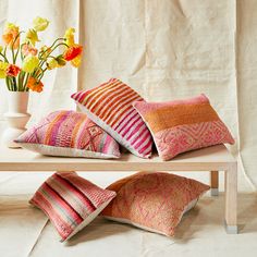 three pillows on a table with flowers in the background