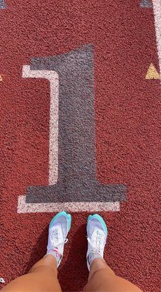 a person's feet standing in front of a number one on a running track