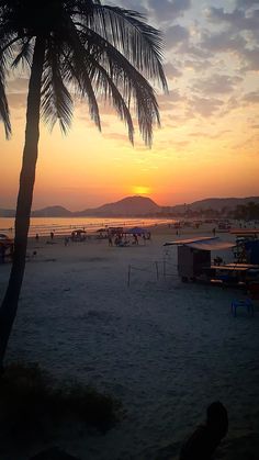 the sun is setting at the beach with people on it