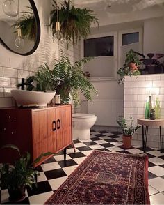 a bathroom with black and white checkered flooring, potted plants on the wall