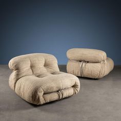 a chair and ottoman sitting next to each other on a gray floor in front of a blue wall