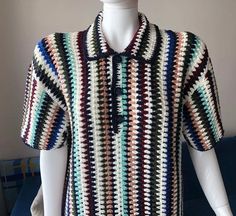 a white mannequin wearing a multicolored crocheted shirt