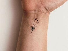 a woman's wrist with a dandelion tattoo on the left side of her arm