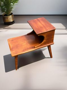 a small wooden table sitting on top of a floor next to a potted plant