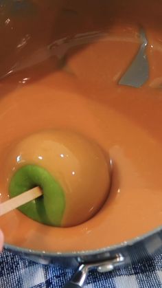 a person is stirring something in a saucepan with a wooden spoon and green pepper