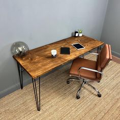 an office desk with a tablet on it and a leather chair in front of it