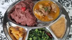 a metal plate topped with different types of food on top of a floral table cloth