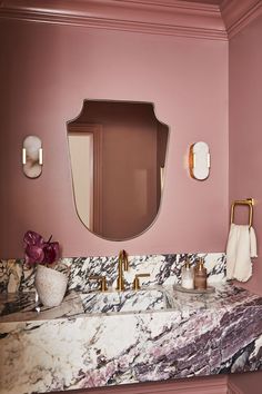 a bathroom with pink walls and marble counter tops