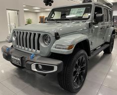 a gray jeep is parked in a showroom