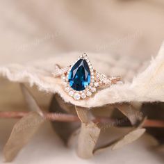 a close up of a ring with a blue stone in it on top of a leaf