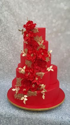 a red three tiered cake with gold flowers on top