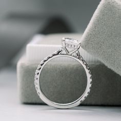 a diamond ring sitting on top of a white cloth next to a cushioned pillow