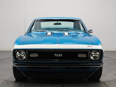 a blue and white muscle car is parked in a room with black tile flooring