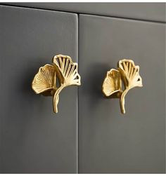 two gold flower shaped hooks on the side of a gray wall