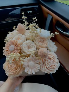 a bouquet of flowers is being held up in the back seat of a car by someone's hand