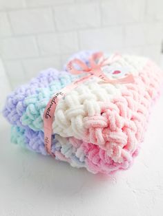 three crocheted washcloths are stacked on top of each other with a pink ribbon