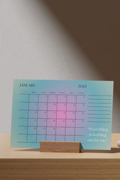 a desk calendar sitting on top of a wooden table next to a small white ball