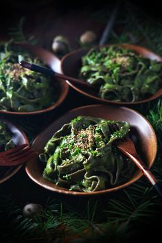 three wooden bowls filled with green pasta and broccoli