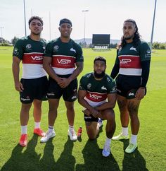 three rugby players pose for a photo on the field