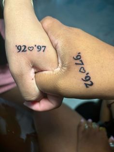 two people holding hands with numbers tattooed on their fingers and the word love spelled in cursive writing