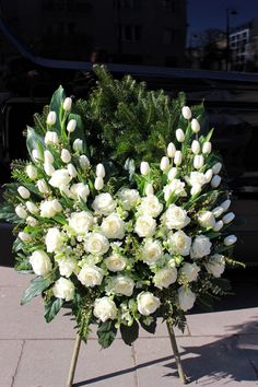 a bunch of white flowers sitting on top of a wooden stand in front of a car