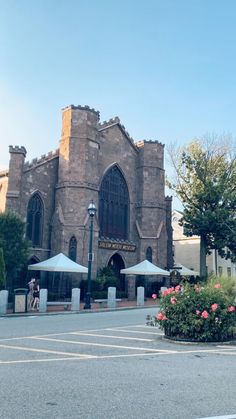 an old church with tables and umbrellas in front