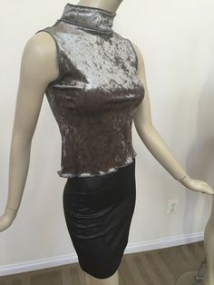 "An unboring foiled velvet turtle neck blouse for holiday parties. Sparkly silver stretch fit sleeveless turtle neck top. Form fitting tank turtle neck in a light grey stretch jersey knit with a lavish spread of sequins. Designed as a slightly cropped style. 17.5\" long from center back neck to hem. Size shown fits women's US 4-6. Model bust is 34-36\". Hand wash warm inside out; air dry." Glamorous Fitted Metallic Tank Top, Velvet Stretch Top For Party, Glamorous Stretch High Neck Tops, Glamorous High Neck Stretch Top, Elegant High Neck Tank Top For Party, Velvet Stretch Tops For Night Out, Silver Fitted Tank Top For Party, Fitted Turtleneck Top For Party, Fitted Sleeveless Holiday Tops